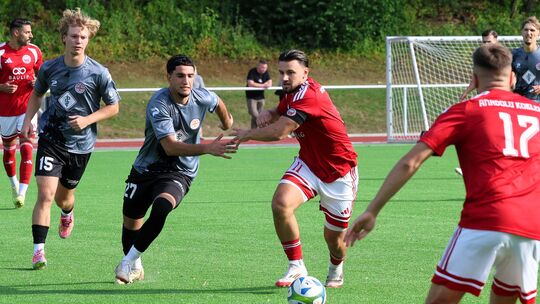Anadolu-Kapitän Durmi Jusufi (rotes Trikot) im Laufduell mit Rot-Weiss-Spieler Majd Abou Shaker (graues Trikot, Nummer 27) - Ana