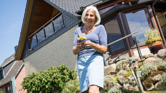 Eine Frau steht im Garten vor ihrem Haus Eine Frau steht im Garten vor ihrem Haus