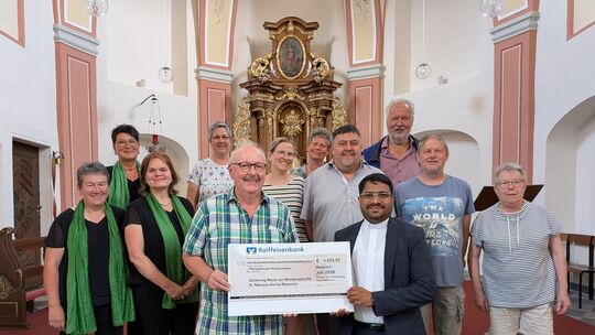 Jijo Antony, Pfarrei der Pfarrei Moselkrampen, nimmt einen Spendenscheck über rund 5000 Euro entgegen. Das Geld dient zur Gegenf