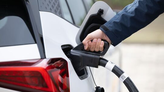 Ein Mann steckt ein Ladekabel in ein Elektroauto Ein Mann steckt ein Ladekabel in ein Elektroauto
