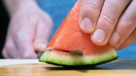 Mann schneidet eine Wassermelone