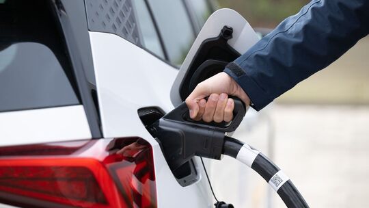 Ein Mann steckt ein Ladekabel in ein Elektroauto Ein Mann steckt ein Ladekabel in ein Elektroauto