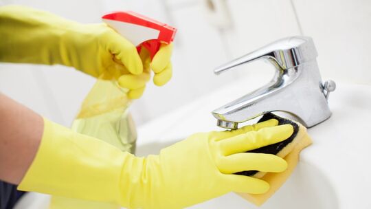 Eine Frau putzt das Waschbecken mit Reinigungsmittel Eine Frau putzt das Waschbecken mit Reinigungsmittel