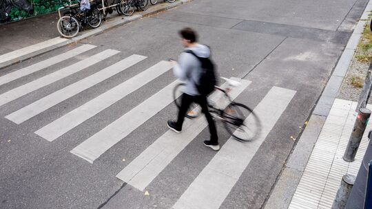 Mann schiebt sein Fahrrad über einen Fußgängerüberweg
