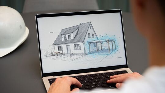 Ein Mann nutzt KI am Laptop für den Hausbau Ein Mann nutzt KI am Laptop für den Hausbau