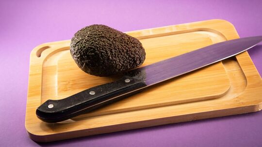 Eine Avocado liegt auf einem Holzbrett