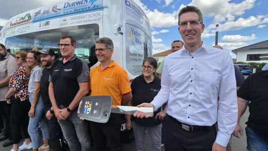 Verbandsbürgermeister Sebastian Busch (rechts) hält den symbolischen Schlüssel für den neuen Kleinbus der VG Pellenz in der Hand