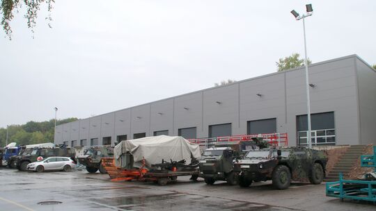 Vor der 2022 neu gebauten Produktionshalle am Südrand des Firmengeländes stehen verschiedene Bundeswehrfahrzeuge, wie ein Fennek Vor der 2022 neu gebauten Produktionshalle am Südrand des Firmengeländes stehen verschiedene Bundeswehrfahrzeuge, wie ein Fennek