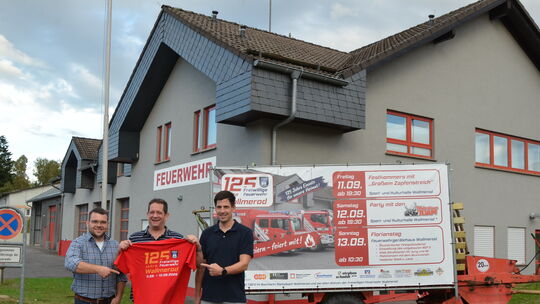 Vor ihrem modernen Gerätehaus machen die Wallmeroder Feuerwehr-Führungskräfte ordentlich Werbung für ihr großes Fest.