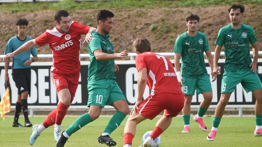 Umzingelt: Der Baumholderer Kapitän Marius Gedratis (grünes Trikot) muss sich in Hüffelsheim spielerisch befreien. Die Szene beo