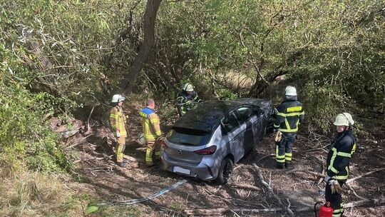Feuerwehrkräfte sichern das Unfallfahrzeug in einem Graben neben der K49 bei Winzenheim.