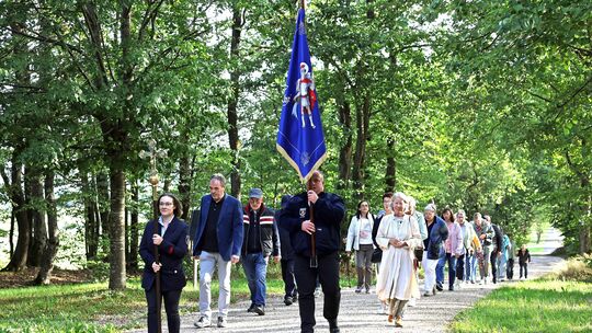 Auf dem Weg zur Kapelle: Arembergs Ortsbürgermeister Thomas Nelles trägt die Traditionsfahne der Freiwilligen Feuerwehr.