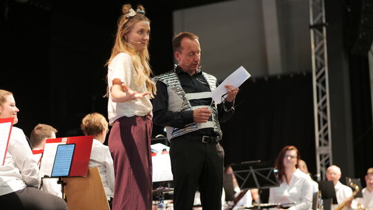 Moderatorin Jana Forkel mit Orchesterleiter Christoph Engers auf der Bühne der neuen Veranstaltungshalle „Deichherz“.
