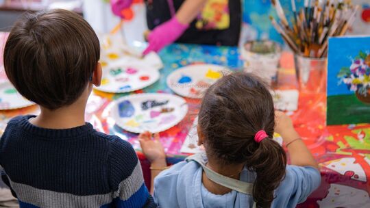 Ein Messestand, an dem zwei Kinder eine kleine Leinwand individuell bemalen