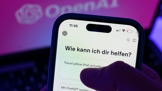 Smartphone mit dem KI-Chatbot ChatGPT vor dem Logo von OpenAI Smartphone mit dem KI-Chatbot ChatGPT vor dem Logo von OpenAI