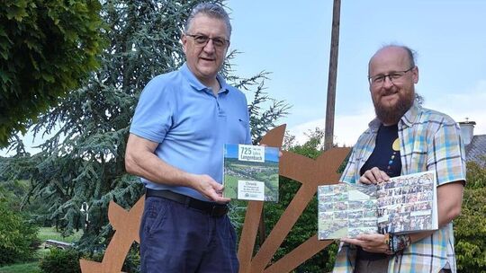 Jochen Schneider (links) und Björn Scheyer stellen die neue, reich bebilderte Langenbacher Chronik vor.