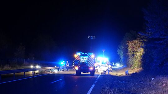 Einsatzkräfte der Feuerwehr sichern die Unfallstelle auf der B41 bei Rüdesheim in der Nacht ab.