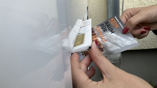 Postkarten mit der Überschrift „Kein Raum für Gewalt“ werden in die Briefkästen der Vonovia-Wohnungen in Koblenz gesteckt.