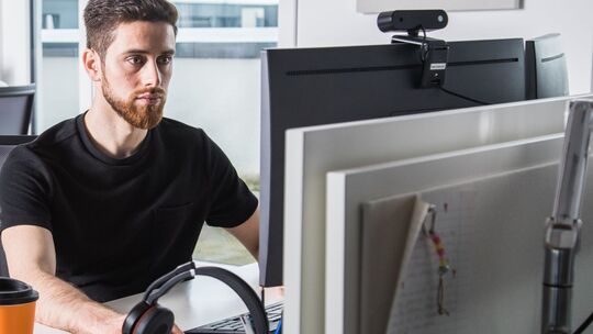 Mann arbeitet vor einem Computerbildschirm Mann arbeitet vor einem Computerbildschirm