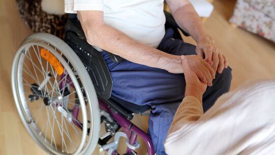 Frau hält die Hände eines zu pflegenden Mannes Frau hält die Hände eines zu pflegenden Mannes