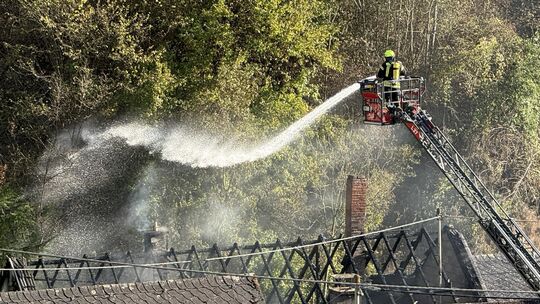 Unter anderem mithilfe einer Drehleiter löscht die Feuerwehr die Flammen in Zell-Merl. Von dem Dachstuhl ist das Gerippe übrig g