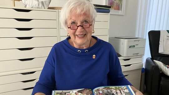 Monika Juraschak ist nun Ordensträgerin. Sie zeigt den Orden (in der Hand) zusammen mit der kleinen Dokumentation eines besonder