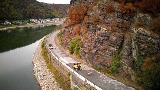 Bauarbeiter bringen auf der Fahrbandecke der B42 am Loreleyfelsen eine Schutzschicht aus Sand auf. Nach dem Felssturz Ende Augus