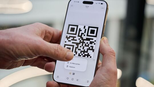 Ein Mann drückt auf einen QR-Code auf einem iPhone Ein Mann drückt auf einen QR-Code auf einem iPhone
