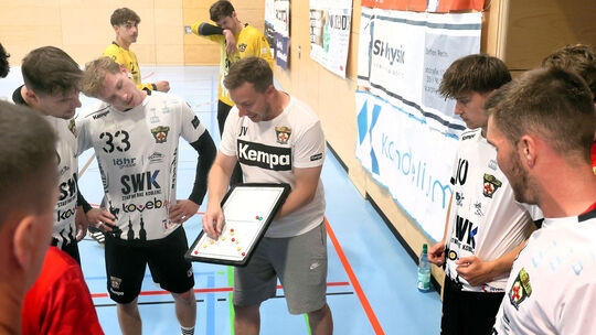 HCK-Trainer Julian Vogt (mit Taktiktafel) gibt seinen Spielern Anweisungen.