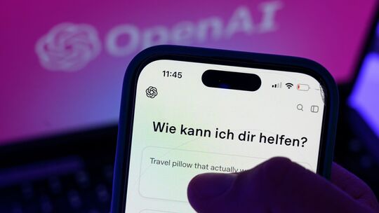 Smartphone mit dem KI-Chatbot ChatGPT vor dem Logo von OpenAI Smartphone mit dem KI-Chatbot ChatGPT vor dem Logo von OpenAI