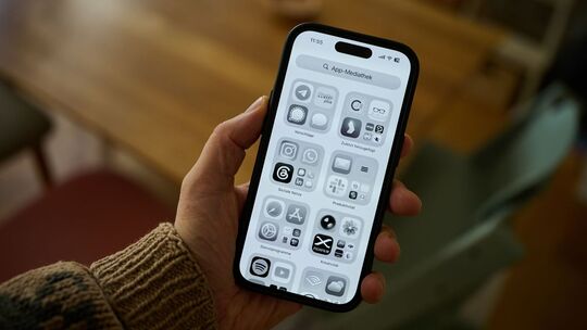 Ein Mann hält ein iPhone mit schwarz-weißem Display in der Hand