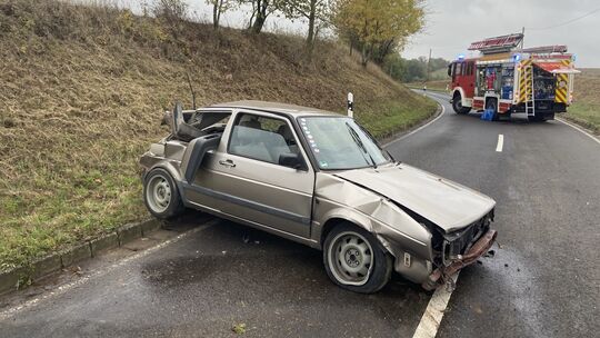 Ein beschädigtes Fahrzeug nach einem Unfall auf der Kreisstraße 66, begleitet von Einsatzkräften der Feuerwehr.