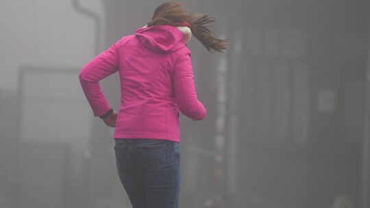 Frau kämpft auf dem Großen Feldberg im Taunus gegen Wind an