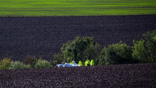 Polizisten untersuchen ein Ultraleichtflugzeug auf einem Ackerfeld bei Fließem. Zwei Menschen sind bei dem Absturz im September