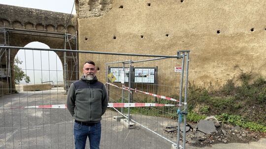 Burgschwalbachs Bürgermeister Daniel Sauerwein vor dem Bauzaun der Baustelle an der Burg.