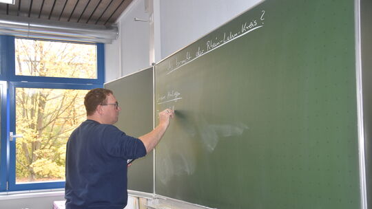 Klassenlehrer Thomas Maier schreibt die Themen, die die Schüler der 9b für die Podiumsdiskussion erarbeitet haben, nochmal an di