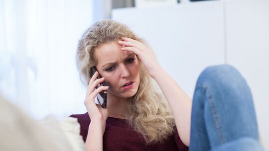 Eine Frau telefoniert besorgt mit dem Handy Eine Frau telefoniert besorgt mit dem Handy